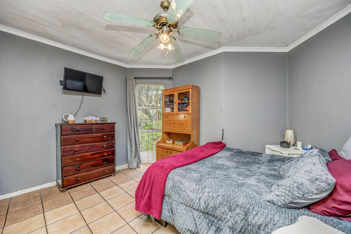 A bedroom featuring tiled flooring, a ceiling fan, and a glass paneled door leading to the exterior.