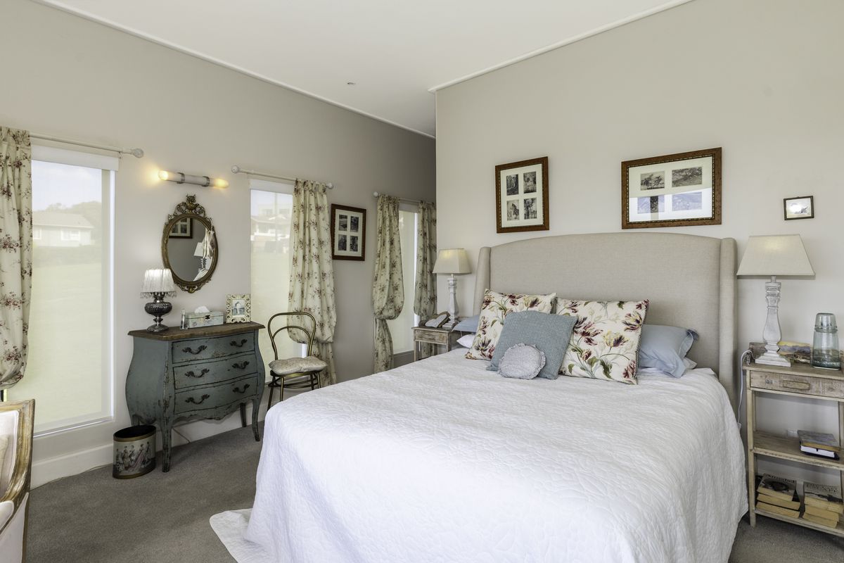 A well-maintained bedroom featuring neutral wall tones, carpeted flooring, and multiple windows that provide ample natural light.