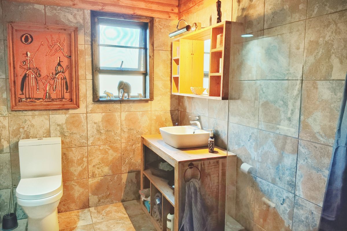 A rustic-style bathroom featuring a vessel sink on a wooden vanity, glass shower screen, and warm-toned ceramic wall and floor tiles.