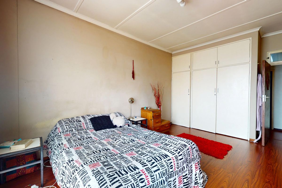 A bedroom featuring laminate flooring and built-in cupboards, offering a functional space with potential for cosmetic updates.