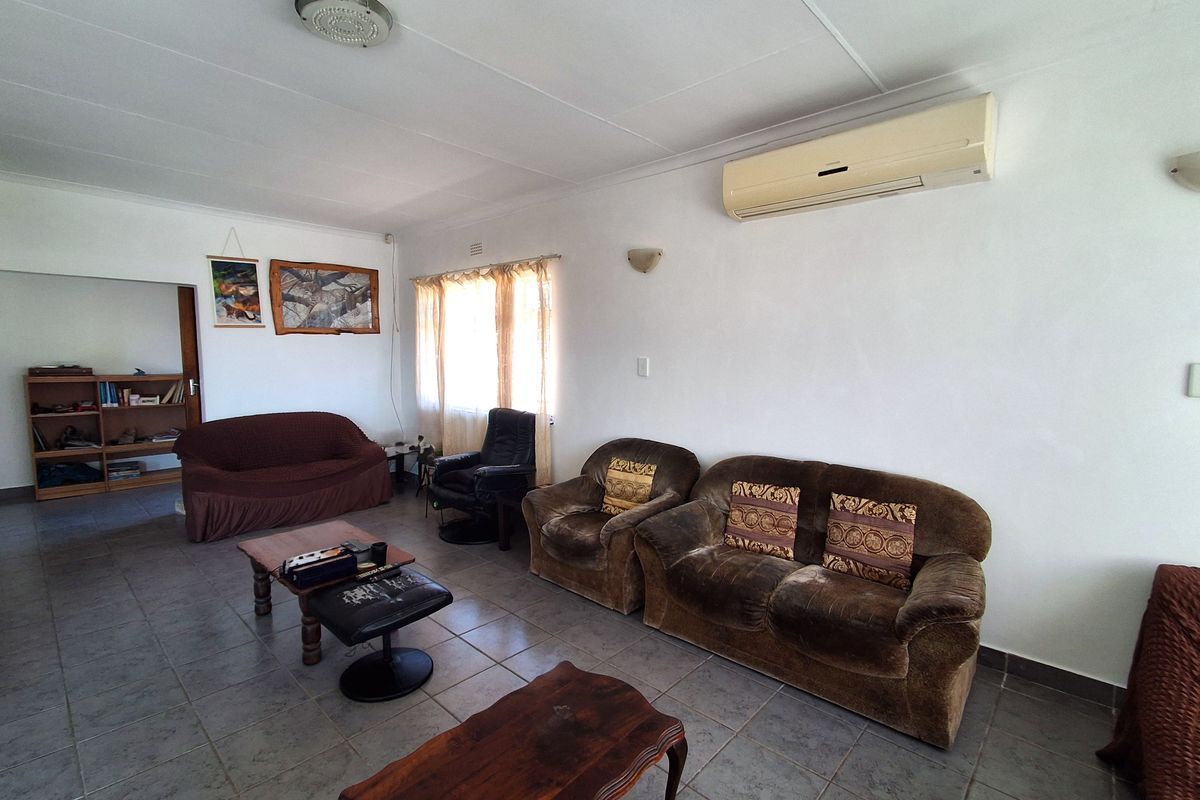A spacious living room featuring tiled flooring, a wall-mounted split-system air conditioner, and neutral wall finishes, offering a functional layout for relaxation.