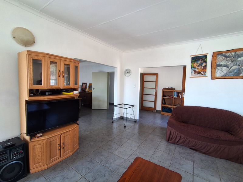 A spacious living area featuring neutral walls, tiled flooring, and coved ceilings, providing a functional layout with access to adjacent rooms.