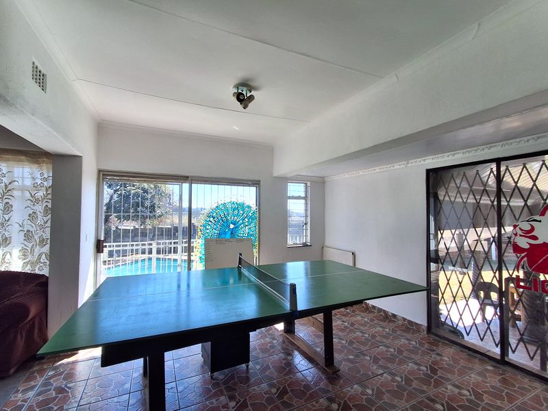 Spacious living area featuring ceramic tile flooring, large sliding glass doors with security gates, and direct access to the outdoor pool area.