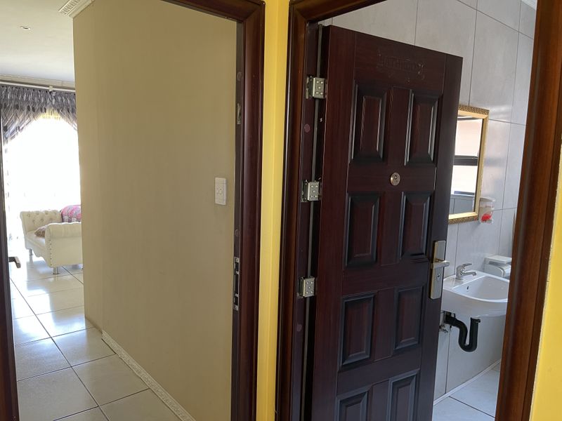 A view of a hallway leading to a bathroom with a vanity and tiled flooring, showing a clean and functional layout.