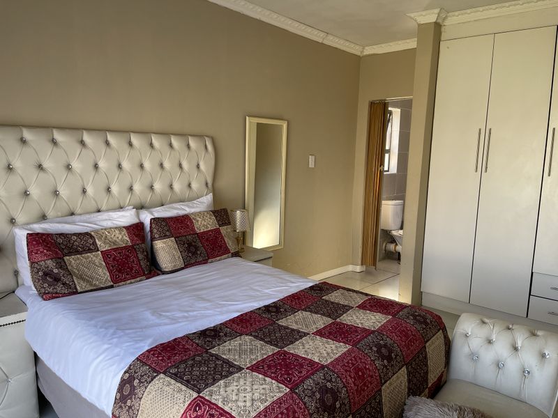 A bedroom featuring built-in wardrobes, crown molding, and an attached en-suite bathroom with a toilet.