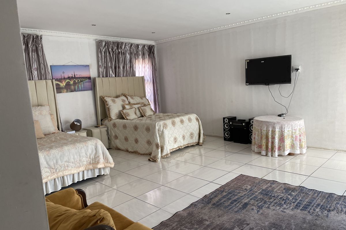Spacious bedroom featuring tiled flooring, recessed downlighting, and decorative ceiling cornicing.