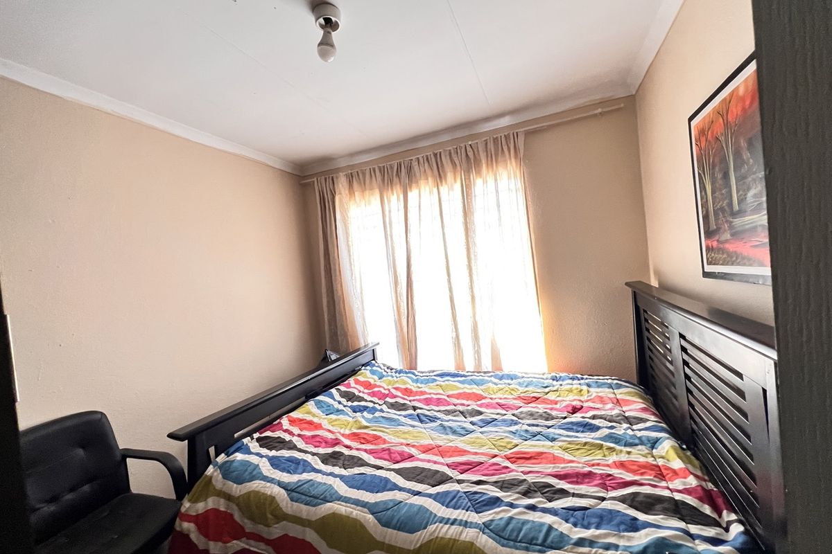 A standard bedroom featuring neutral wall finishes, a curtain rail, and coving detail.