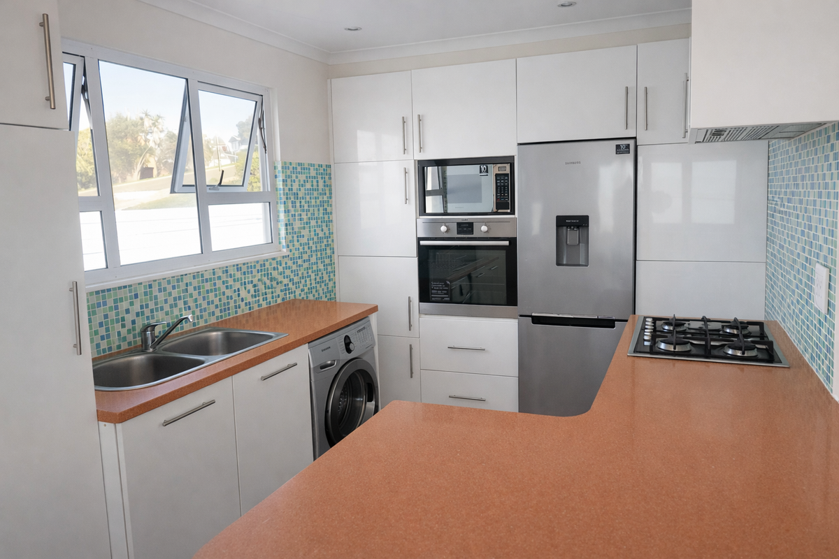 Modern kitchen featuring white cabinetry, mosaic tile backsplash, integrated appliances including an oven, microwave, and gas hob, with ample counter space.