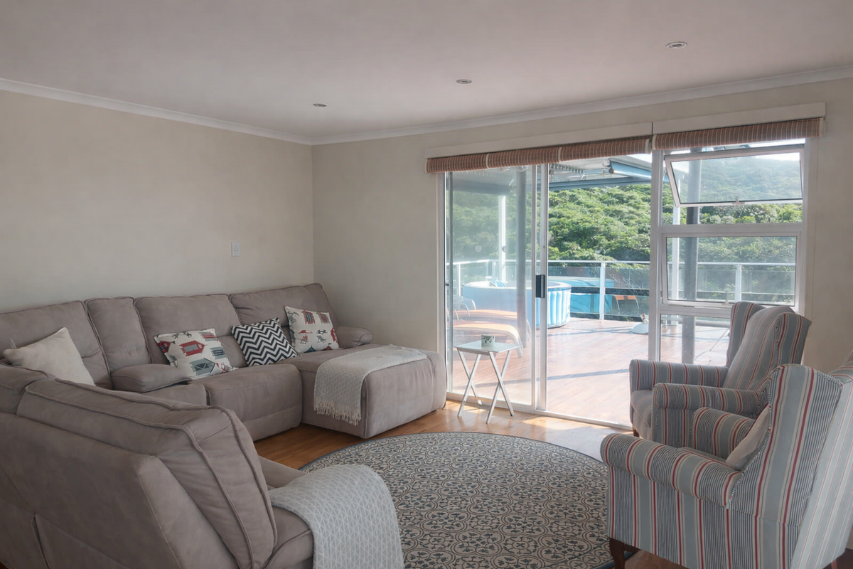 A bright living room featuring timber flooring, recessed lighting, and large sliding glass doors that provide seamless access to an outdoor deck area.