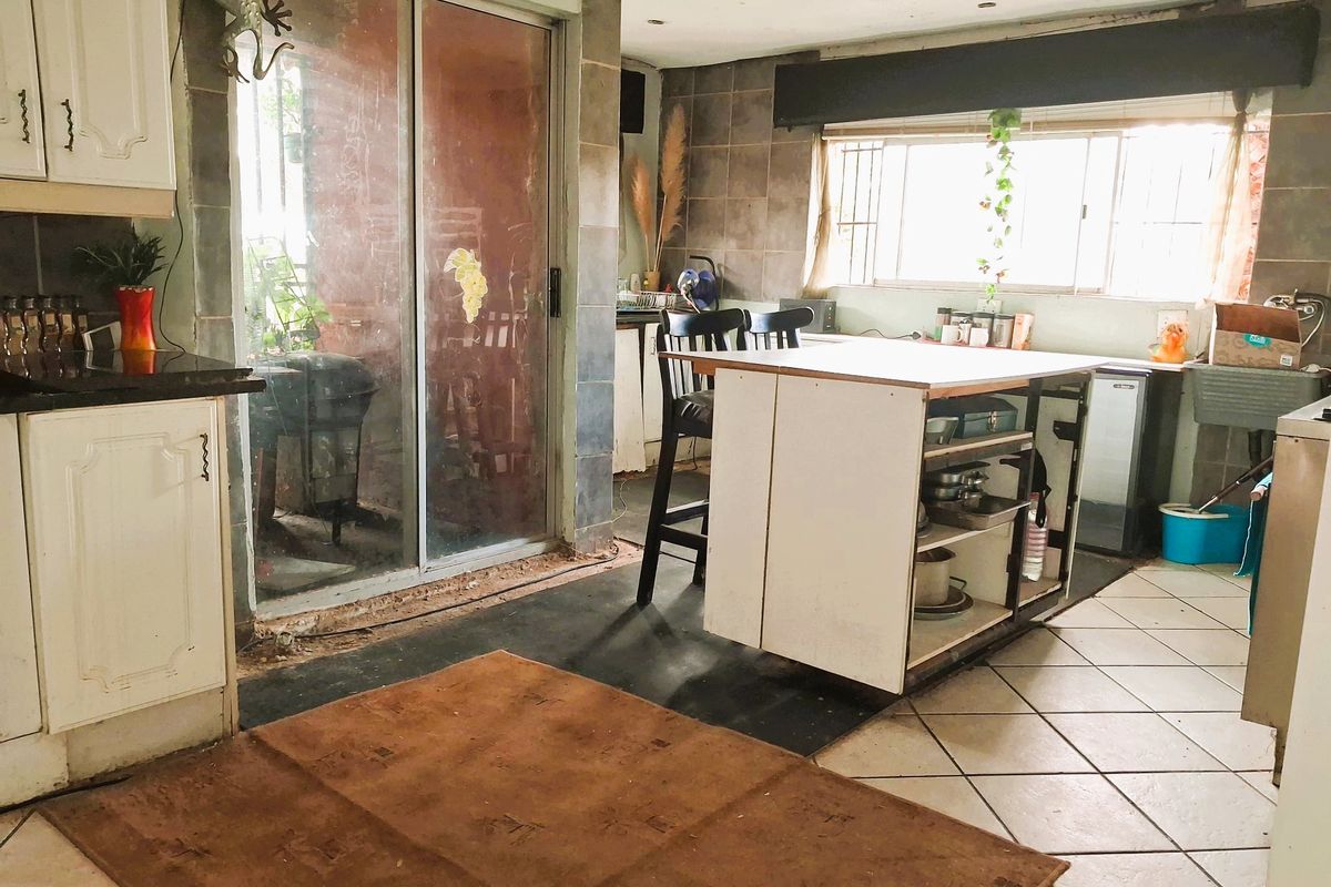 A dated kitchen featuring granite countertops, a central island, and direct access to the outdoor area through a sliding glass door.