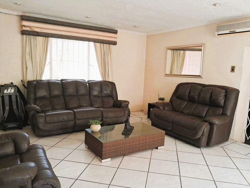 A spacious living room featuring tiled flooring, recessed downlighting, and a wall-mounted air conditioning unit.