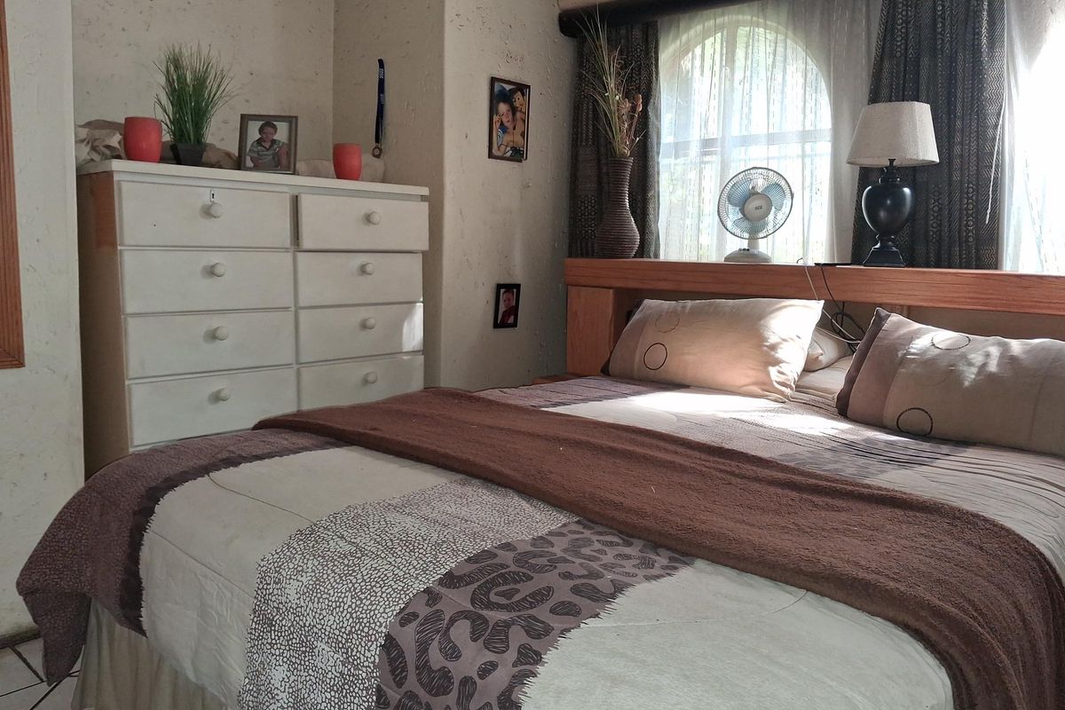 A bedroom featuring a textured wall finish and an arched window, providing a cozy and functional sleeping space.