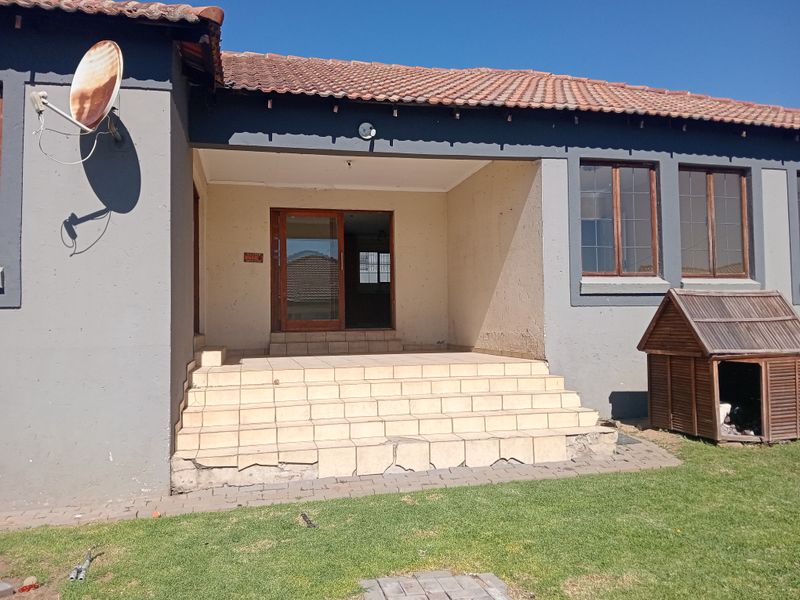 Rear exterior view of the house featuring a tiled patio area with sliding door access and a terracotta tiled roof.
