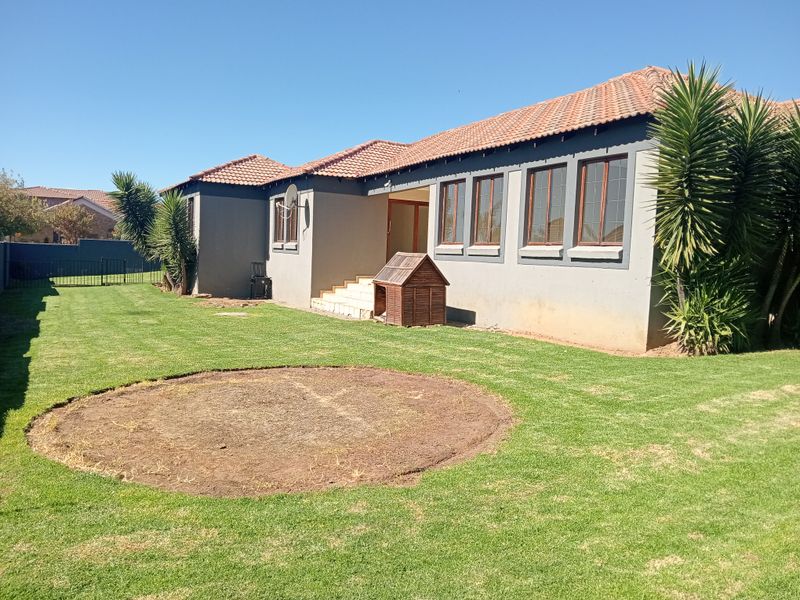 Rear view of the house featuring a tiled roof, concrete steps, and a spacious garden with a lawn.