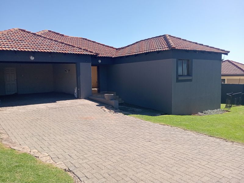 Front view of a residential property featuring a paved driveway, double garage, and tiled roof with dark exterior paint.
