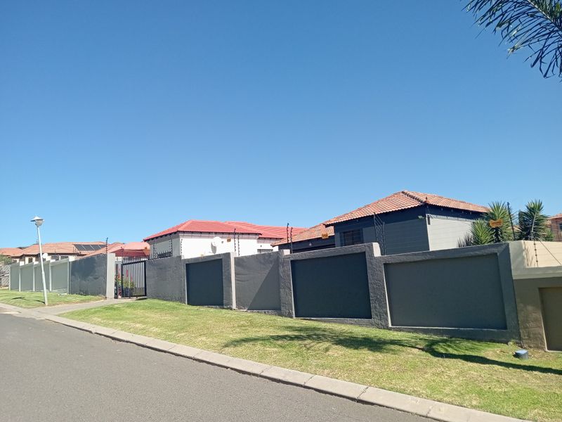 Street view of the property showing the perimeter wall, electric fencing, and tiled roof structures.