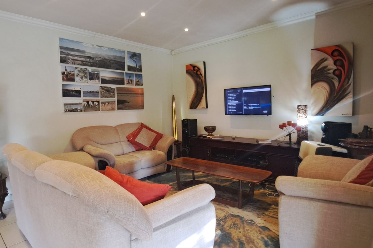 A comfortable living room featuring tiled flooring, recessed ceiling lighting, and a wall-mounted television setup.