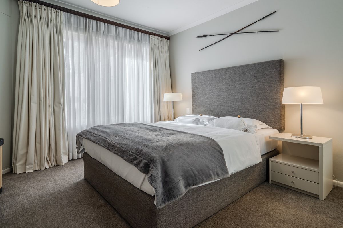 A well-maintained bedroom featuring neutral carpeting, floor-to-ceiling curtains, and coved ceiling detailing.