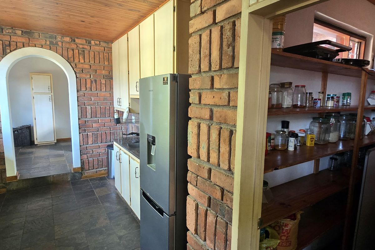 Kitchen featuring exposed brick walls, slate flooring, and timber ceiling, with an adjacent walk-in pantry area and built-in cabinetry.
