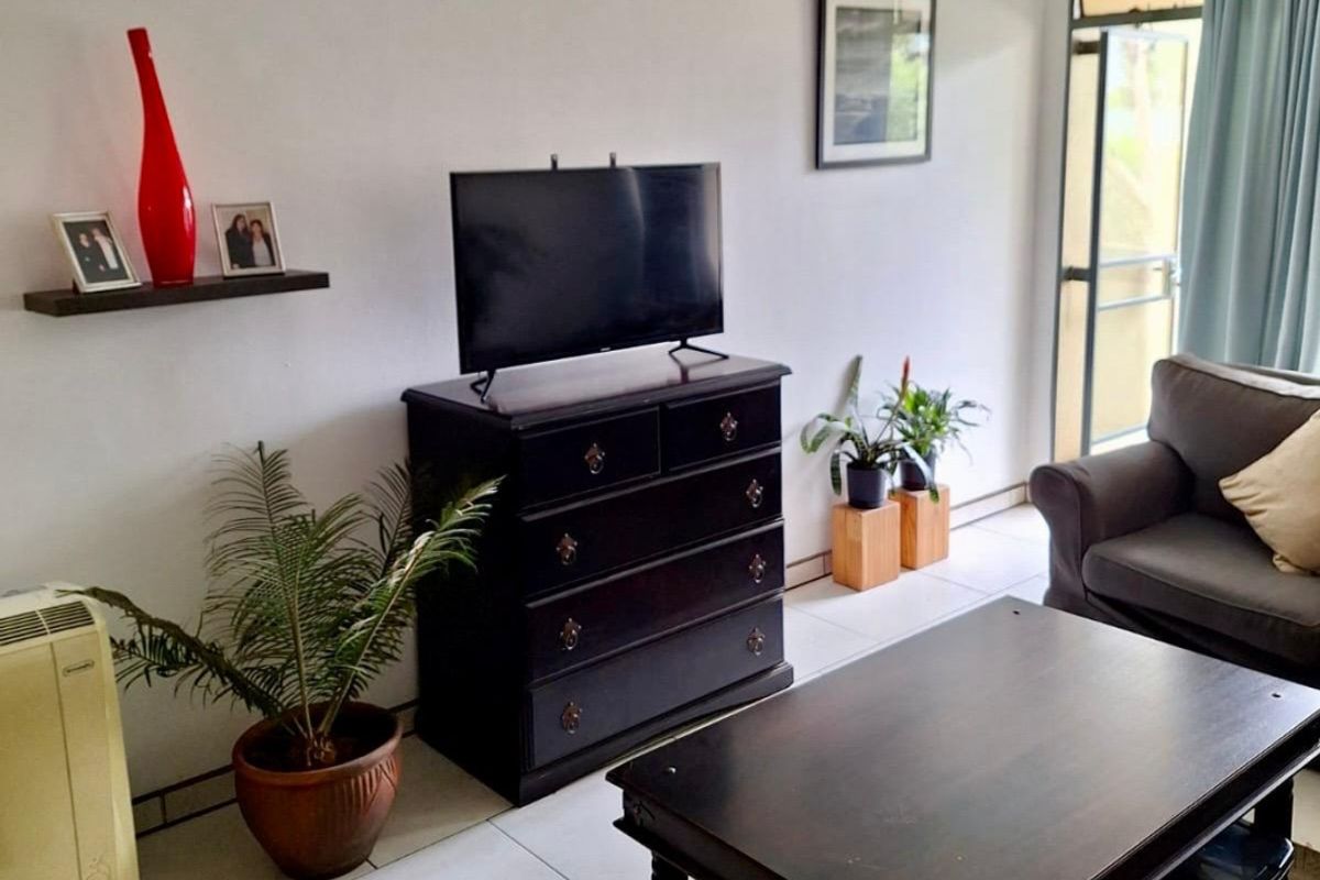 A living room area featuring tiled flooring and a sliding glass door providing access to the exterior.
