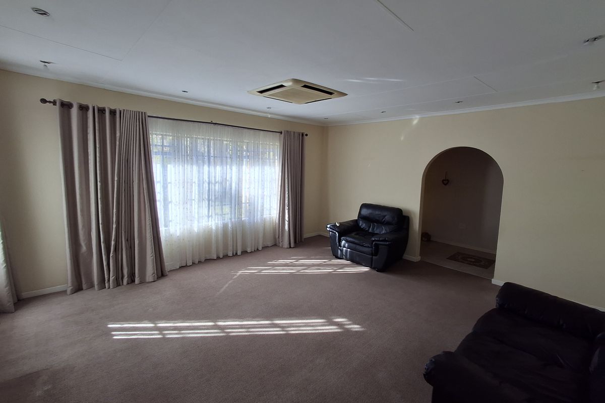 Spacious living room featuring an archway entrance, ducted air conditioning, and large windows with neutral wall finishes.