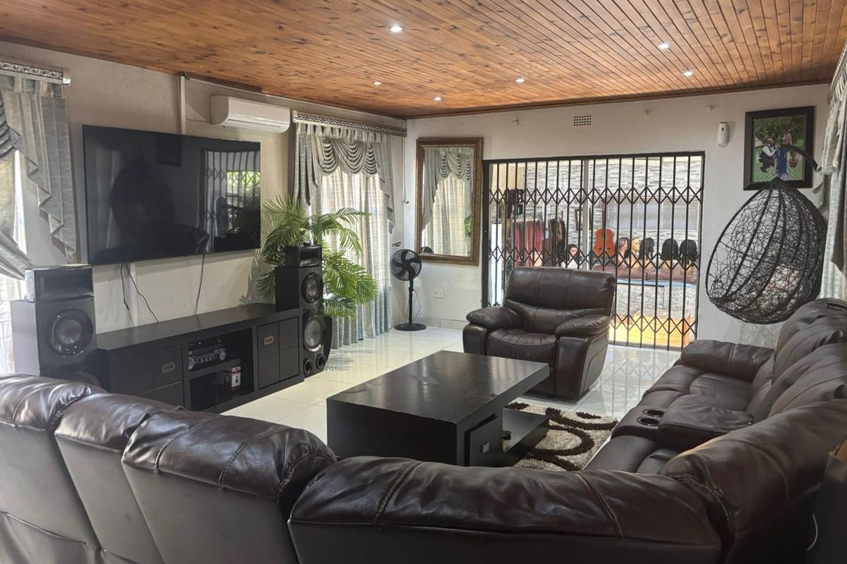 Spacious living room featuring a timber-clad ceiling, recessed downlighting, tiled flooring, and a security gate providing access to the outdoor area.
