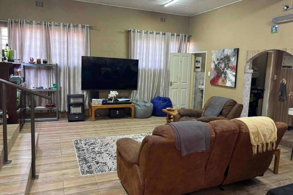 Spacious living room featuring tiled flooring, an air conditioning unit, and an arched entryway leading to adjacent areas.