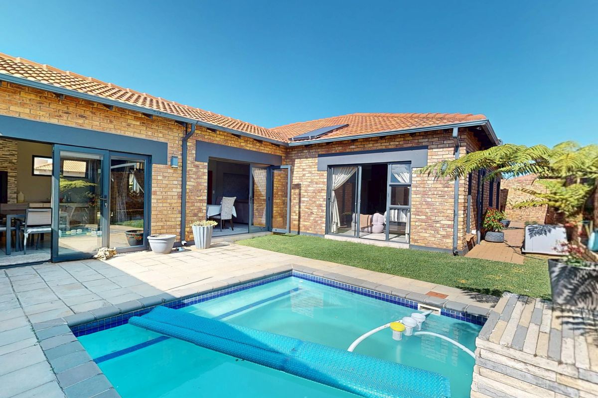 Rear exterior view of the cluster home featuring a private swimming pool, paved patio area, and direct access through sliding glass doors.