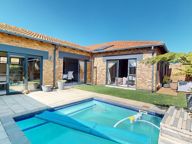 Rear exterior view of the cluster home featuring a private swimming pool, paved patio area, and direct access through sliding glass doors.