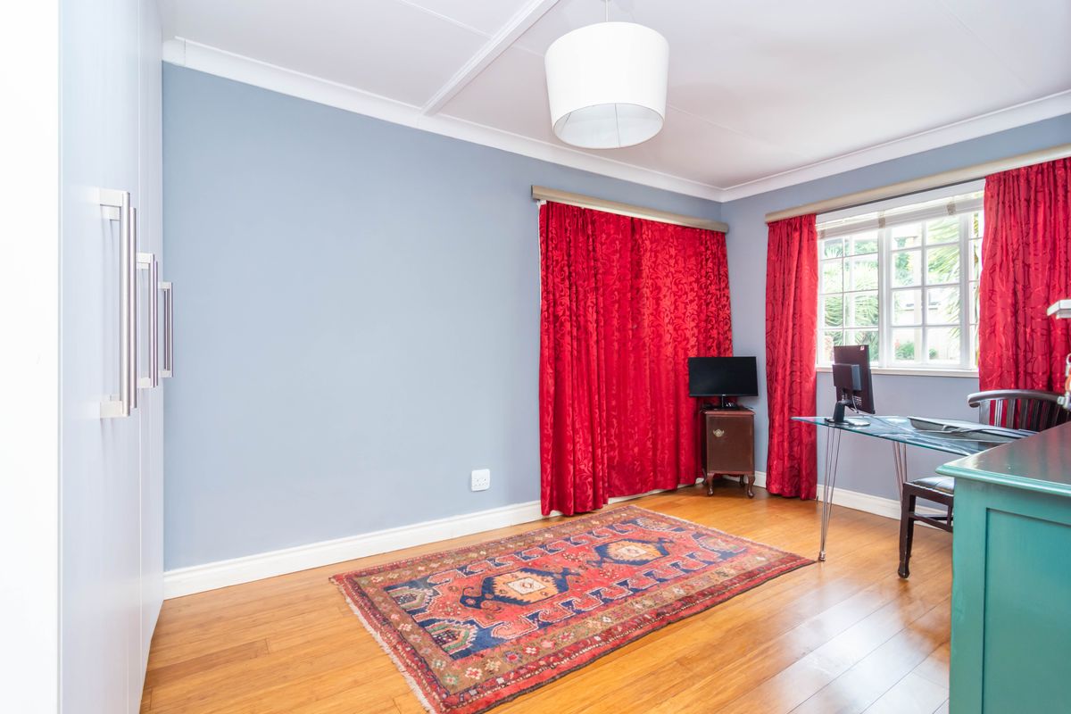 A well-maintained bedroom featuring hardwood flooring, built-in cupboards, and a coved ceiling, offering a clean and functional living space.
