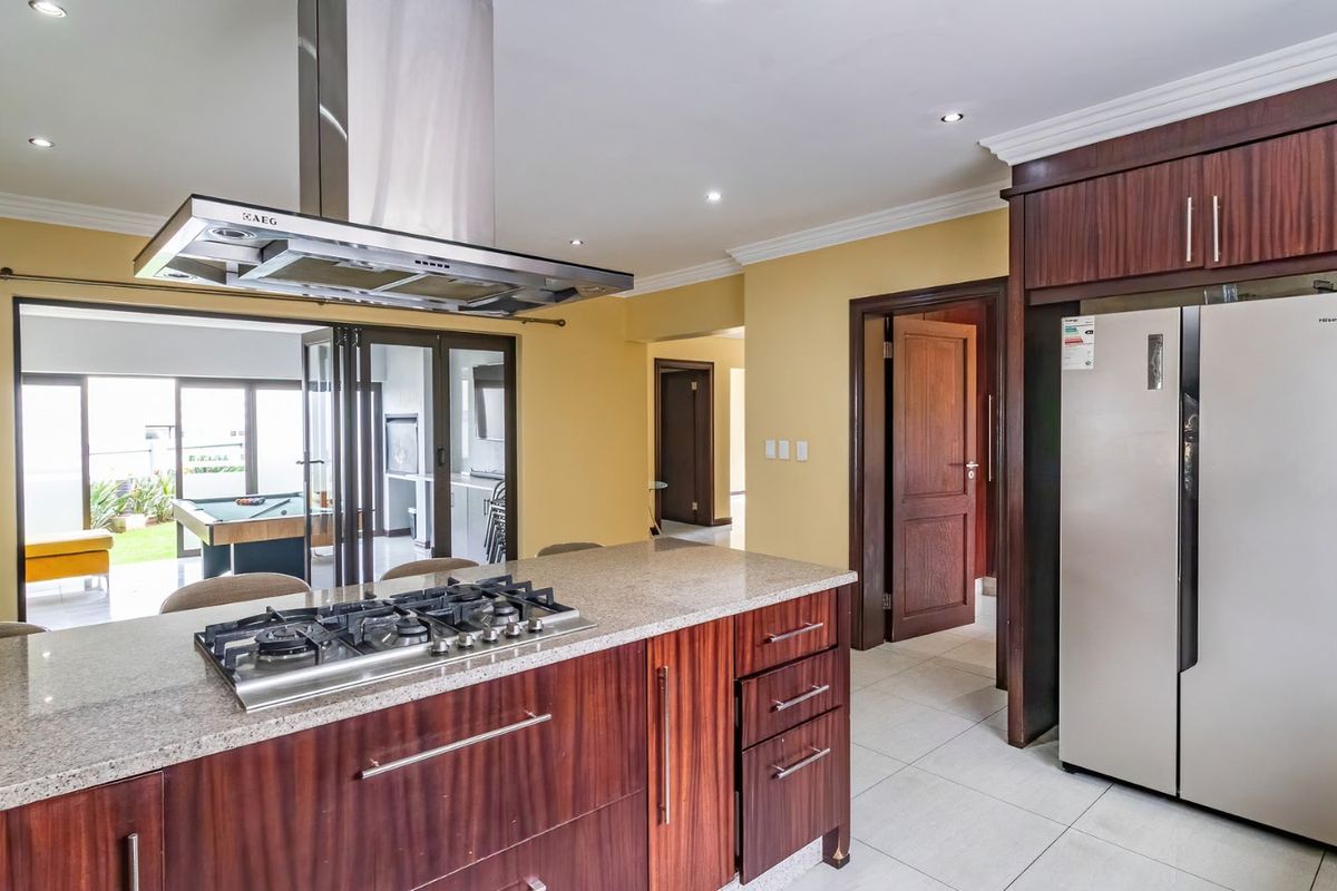 Modern kitchen featuring a central island with a gas hob, stainless steel extractor fan, granite countertops, and dark wood cabinetry.