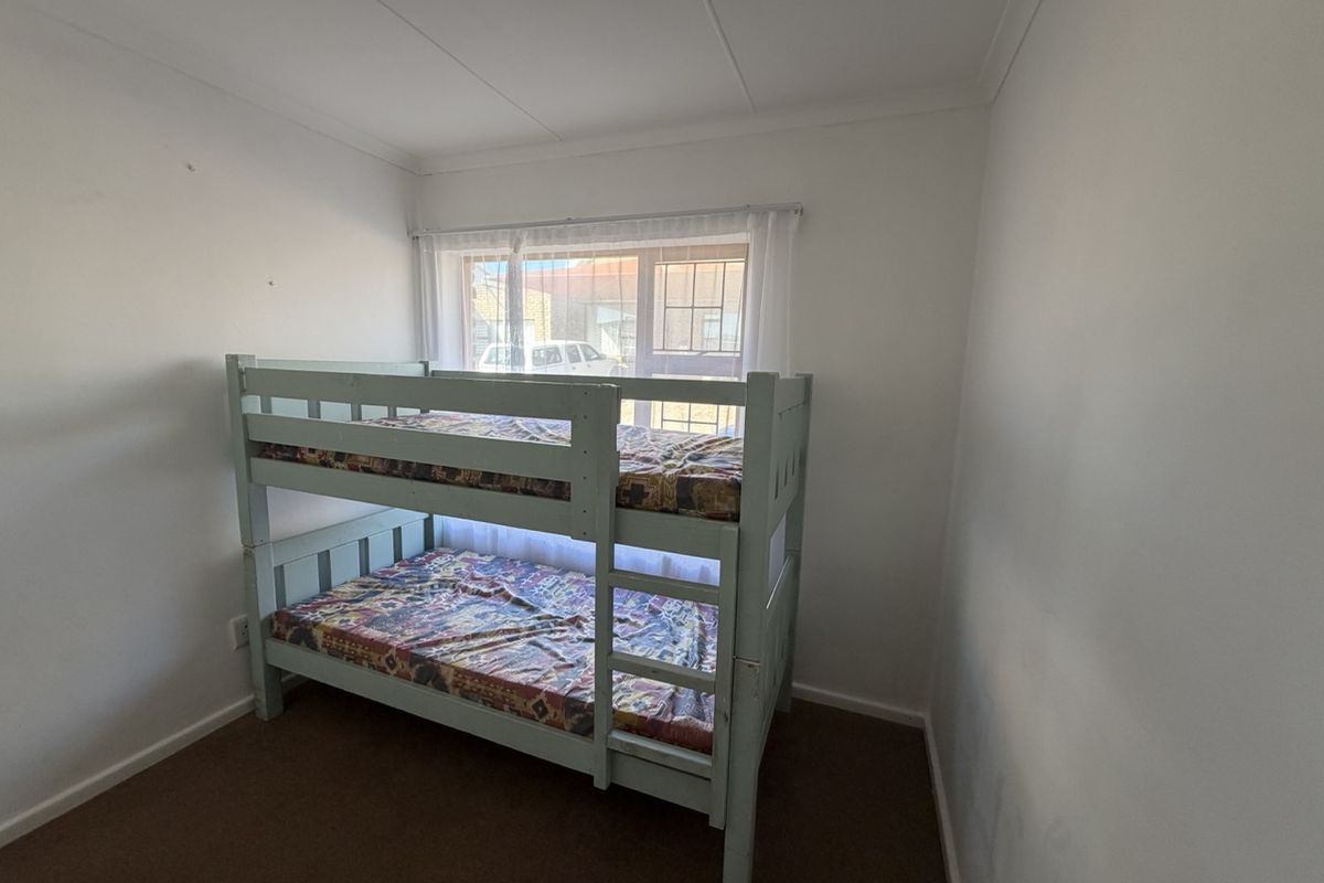 A standard bedroom featuring carpeted flooring, a window with security bars, and coved ceiling detailing.