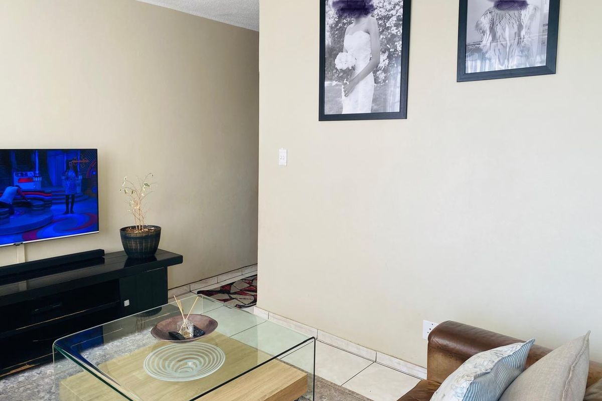A living room area featuring neutral wall finishes and tiled flooring, providing a functional space for relaxation and entertainment.
