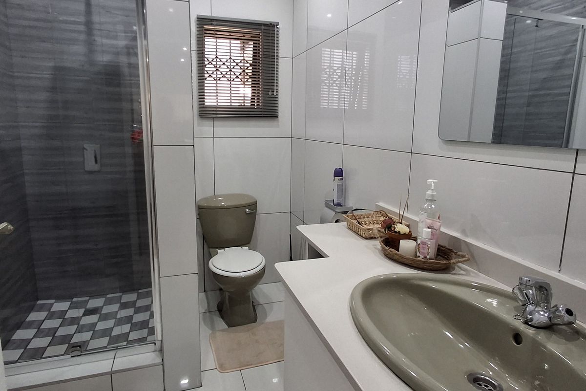 Modern bathroom featuring a glass-enclosed shower, vanity with integrated basin, and neutral tiled finishes throughout.