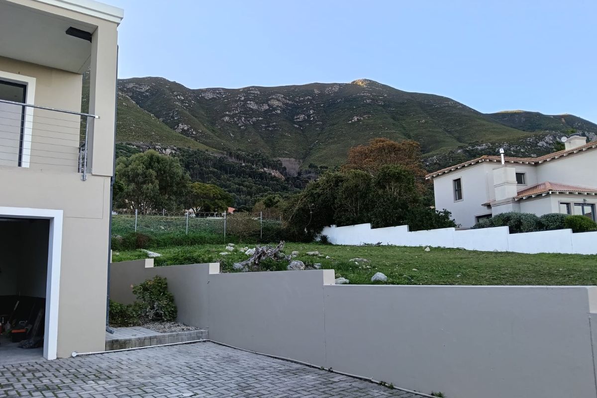 Rear exterior view featuring a paved driveway, retaining wall, and balcony with mountain views.