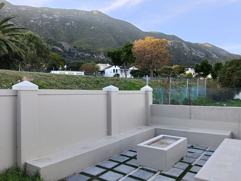 Outdoor patio area featuring built-in concrete seating and a central fire pit, set against a scenic mountain backdrop.