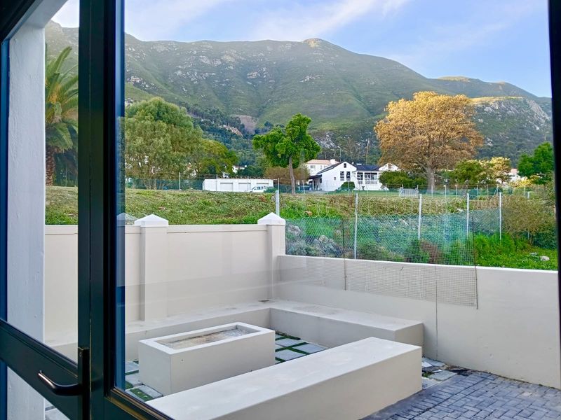 Outdoor patio area featuring built-in concrete seating and a central fire pit, offering scenic mountain views.