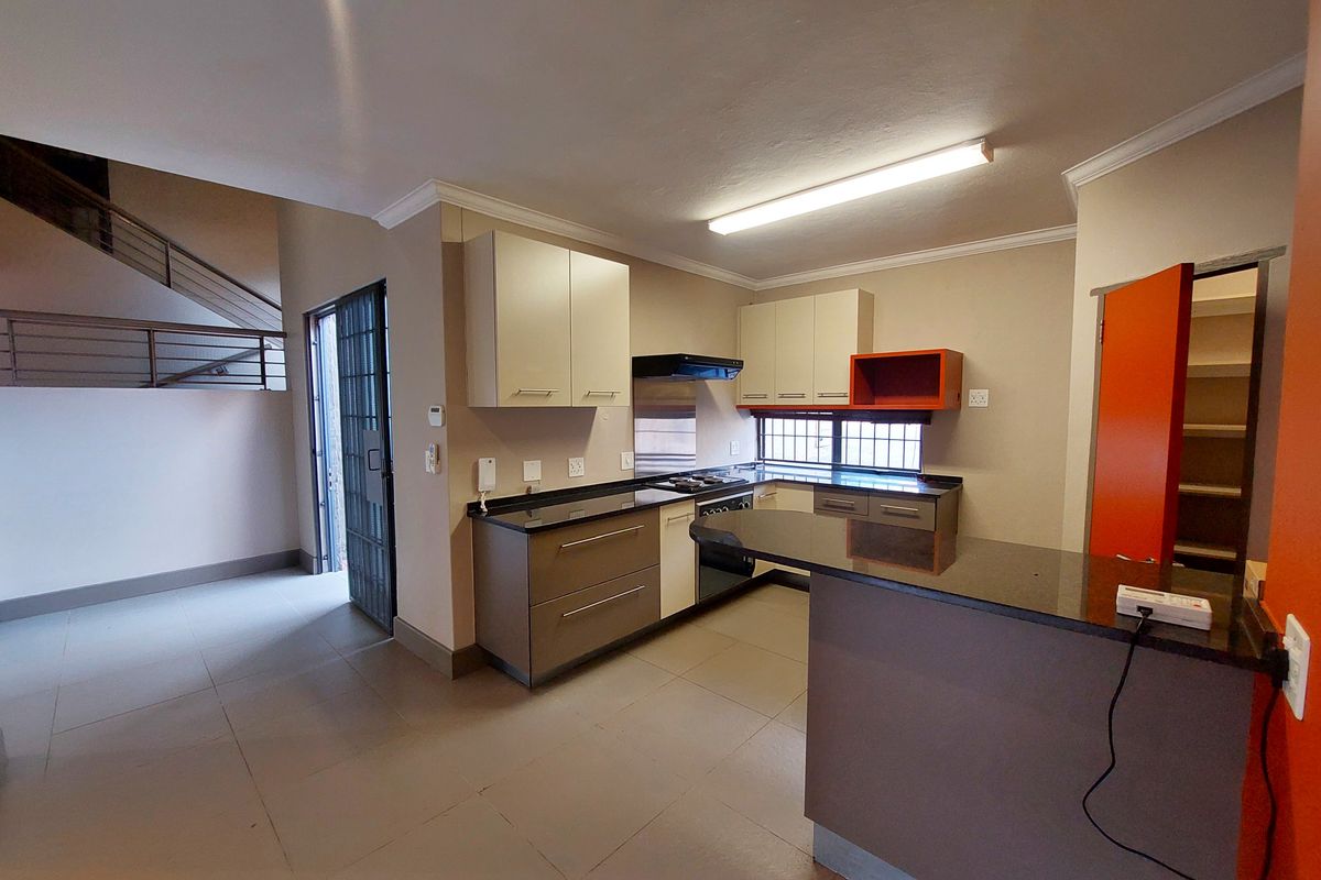 A functional kitchen featuring granite countertops, built-in cabinetry, and a breakfast bar, adjacent to an open staircase and security entrance.