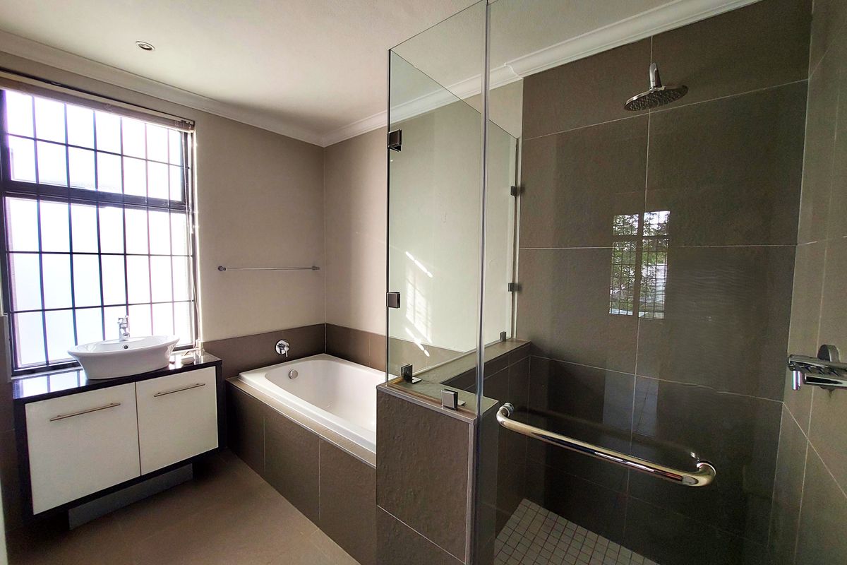 Modern bathroom featuring a built-in vanity with vessel sink, a separate bathtub, and a glass-enclosed shower with a rain shower head.