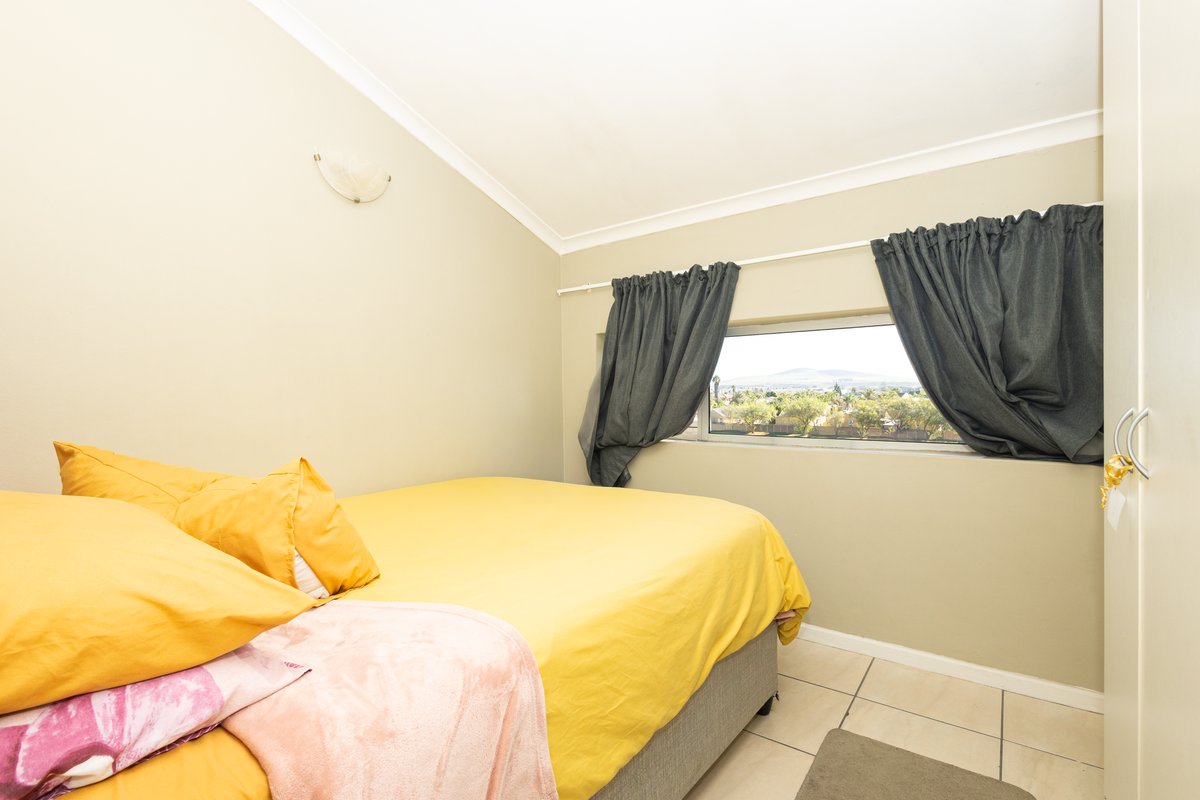 A bedroom featuring tiled flooring, a sloped ceiling, a built-in wardrobe, and a window offering an elevated view.
