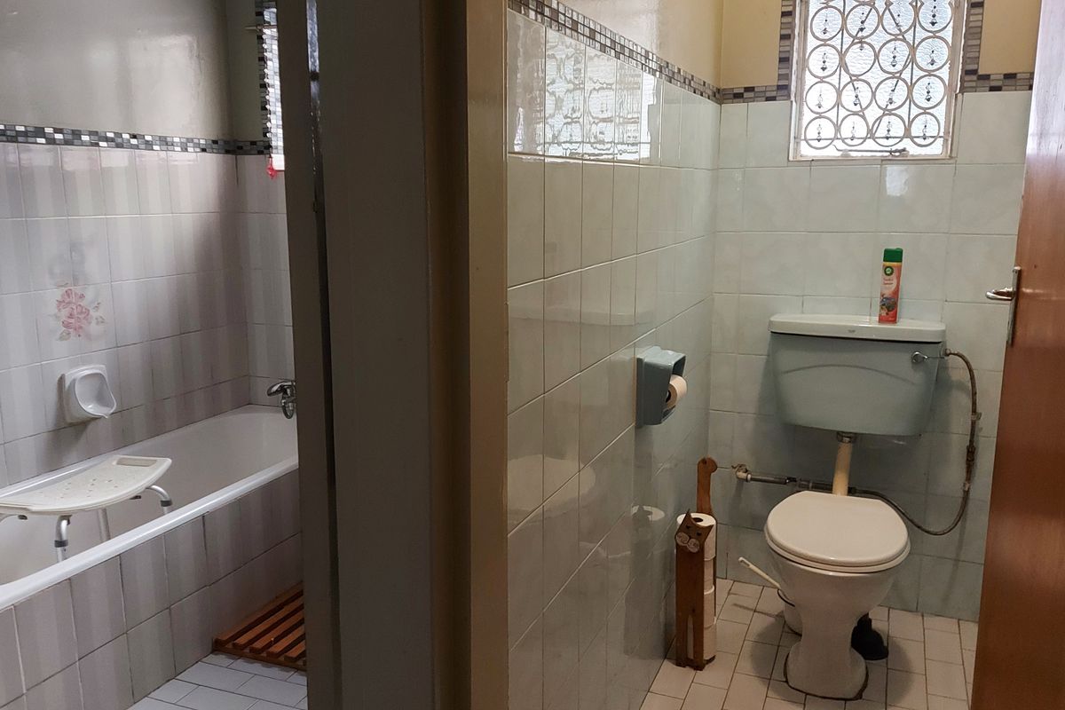 A functional bathroom featuring a bathtub and toilet with classic tiled finishes and decorative border detailing.