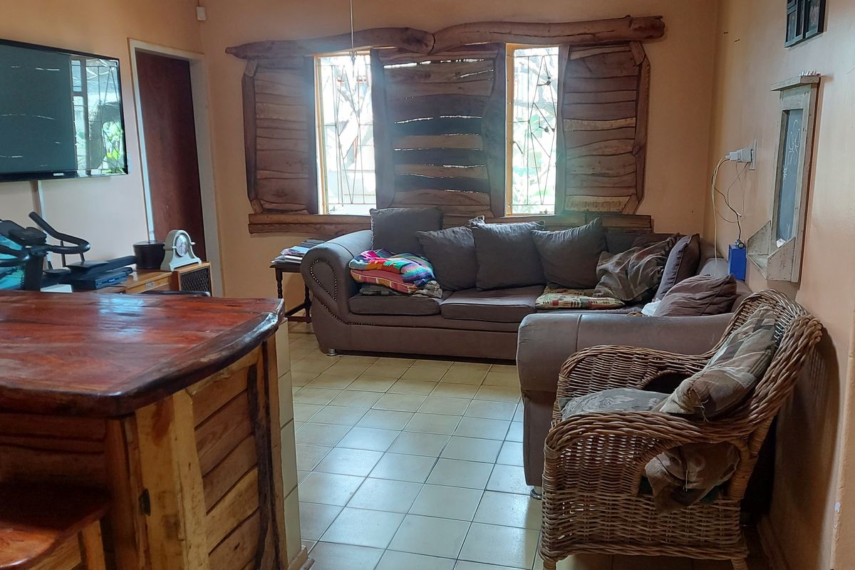 A living room featuring ceramic tile flooring and rustic wooden window surrounds, requiring cosmetic updates to improve the overall aesthetic.