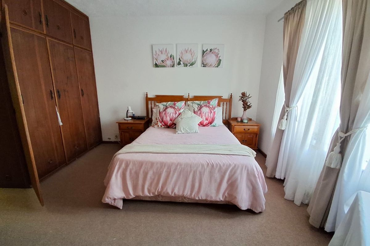 A bedroom featuring built-in wooden cupboards and carpeted flooring, offering a functional and traditional layout.