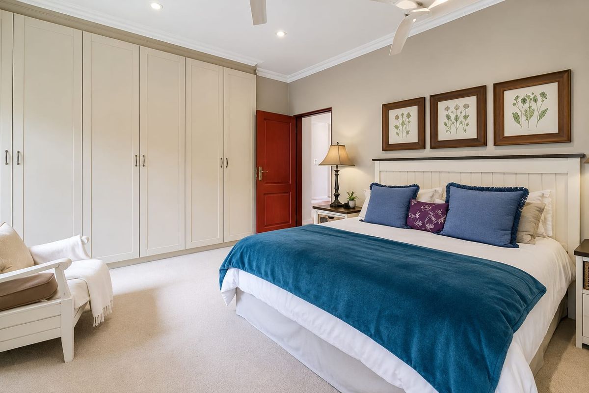 A well-maintained bedroom featuring extensive built-in cabinetry, neutral carpeting, ceiling fan, and recessed lighting, offering a clean and comfortable living space.
