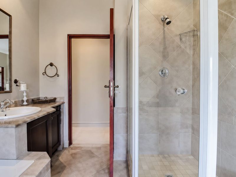 A well-maintained bathroom featuring a vanity with stone countertop, integrated sink, and a separate tiled shower enclosure.
