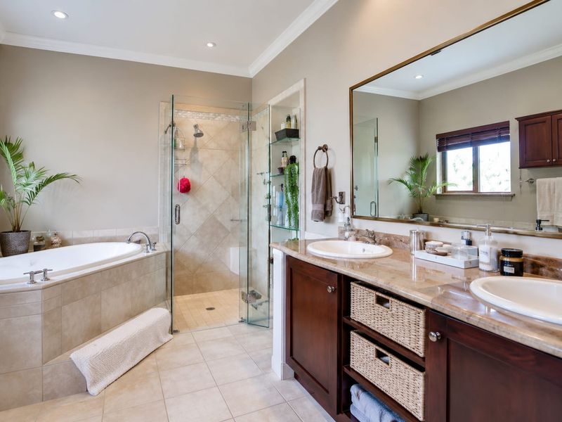 Spacious bathroom featuring a double vanity with stone countertops, a built-in bathtub, and a separate glass-enclosed shower with neutral tile finishes.