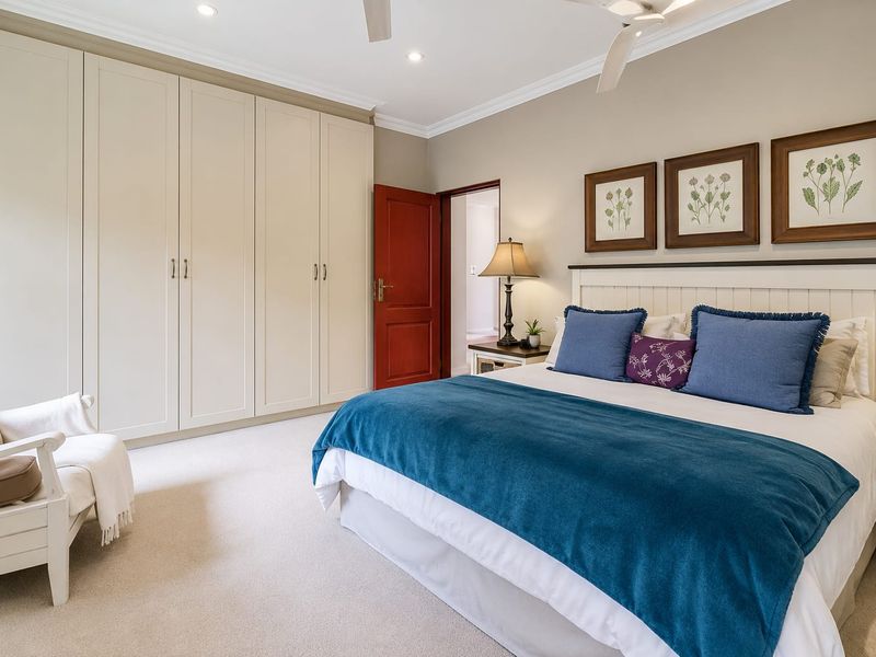 A well-maintained bedroom featuring extensive built-in cabinetry, neutral carpeting, ceiling fan, and recessed lighting, offering a clean and comfortable living space.