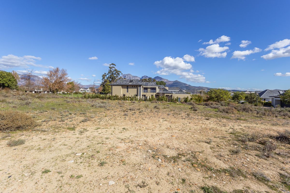 A vacant residential plot of land featuring natural vegetation and scenic mountain views in the background.