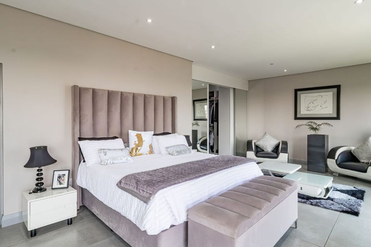 Spacious bedroom featuring neutral wall tones, tiled flooring, recessed downlighting, and built-in mirrored sliding wardrobes.