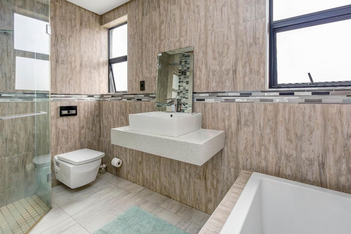 Modern bathroom featuring a floating vanity with vessel sink, wall-mounted toilet, glass shower enclosure, and a built-in bathtub with neutral wood-look wall tiling.